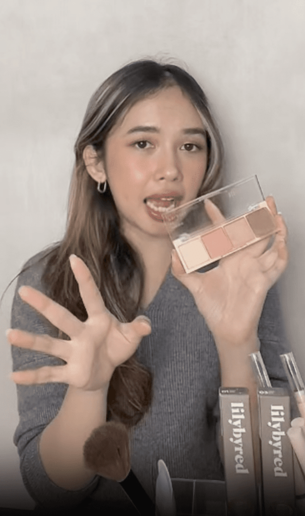 Una joven presenta con entusiasmo una paleta de maquillaje durante una retransmisión en directo, mostrando su presencia en pantalla e interactuando con el público.