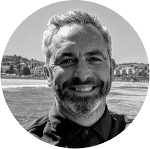 Retrato en blanco y negro de un hombre sonriente con fondo costero